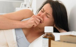 Young woman sneezing in bed